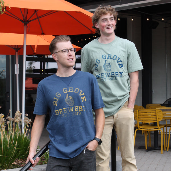 Two men with Big Grove t-shirts, one blue with yellow text, one light gray-green with blue text