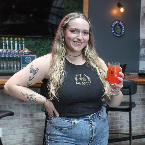 Woman wearing black top and jean shorts holding a drink